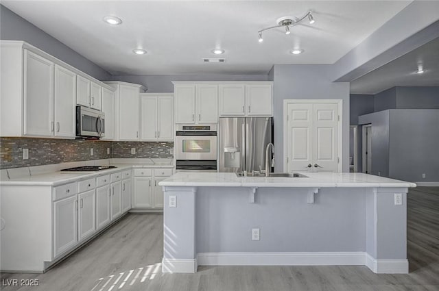 kitchen featuring stainless steel appliances, light wood-type flooring, white cabinets, and a sink