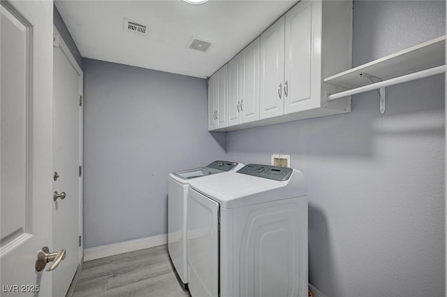 laundry area with light wood finished floors, visible vents, cabinet space, independent washer and dryer, and baseboards