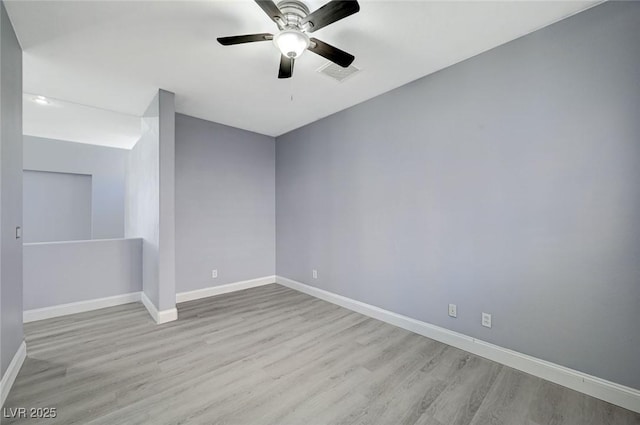 unfurnished room featuring baseboards, visible vents, ceiling fan, and wood finished floors