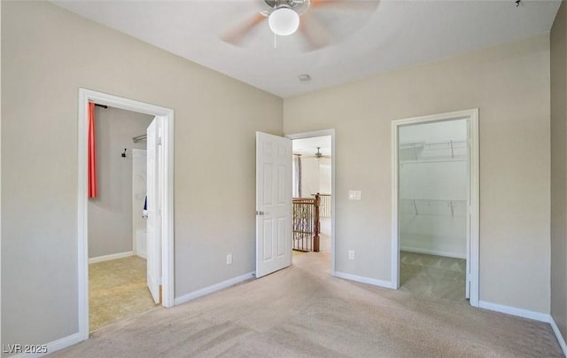 unfurnished bedroom featuring ensuite bath, ceiling fan, light carpet, a walk in closet, and a closet