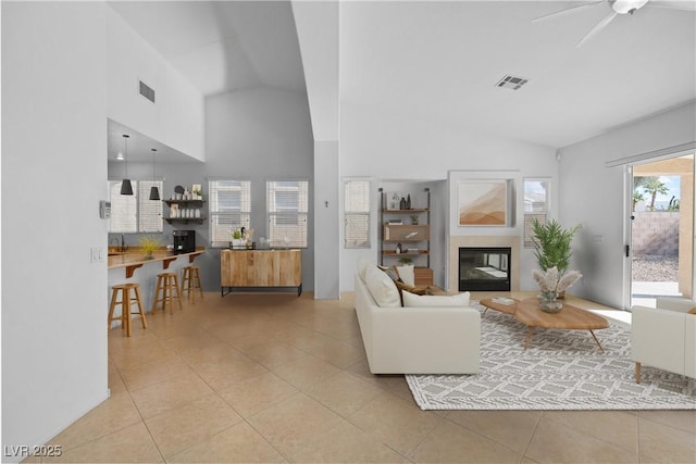 living area with light tile patterned flooring, a glass covered fireplace, and visible vents