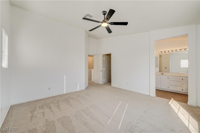 unfurnished bedroom featuring vaulted ceiling, light colored carpet, ceiling fan, and ensuite bathroom