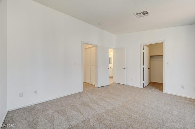 unfurnished bedroom with a spacious closet and light colored carpet