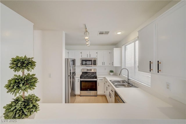 kitchen featuring white cabinetry, appliances with stainless steel finishes, sink, and light hardwood / wood-style flooring