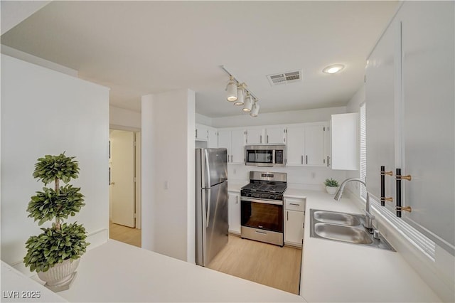 kitchen with white cabinetry, sink, stainless steel appliances, and light hardwood / wood-style floors