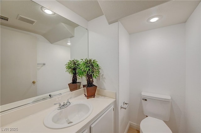 bathroom with vanity, toilet, and a textured ceiling