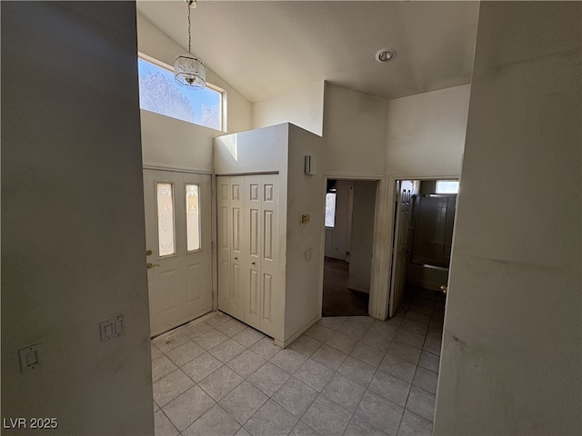 tiled foyer entrance featuring high vaulted ceiling