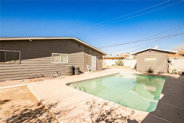 view of swimming pool with a storage shed and a patio area