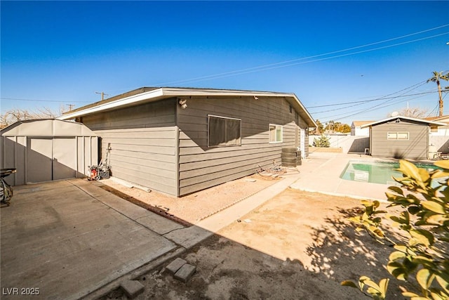 rear view of house with a storage unit, a fenced in pool, and a patio