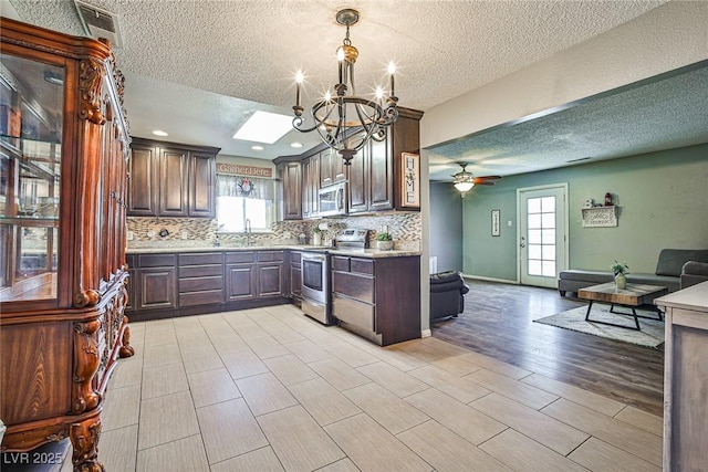 kitchen with stainless steel appliances, sink, dark brown cabinetry, and decorative light fixtures