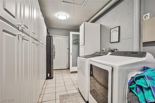 washroom with cabinets, light tile patterned floors, and washing machine and clothes dryer