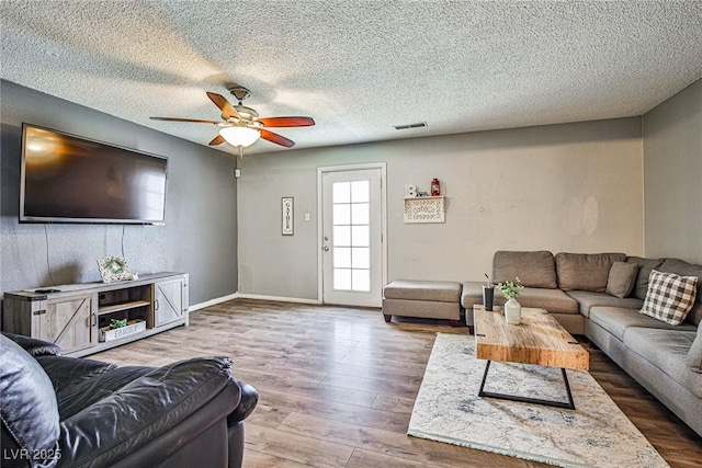 living room featuring ceiling fan, hardwood / wood-style floors, and a textured ceiling