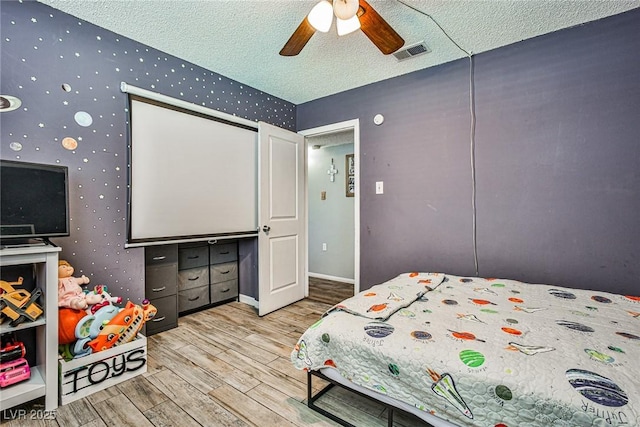 bedroom featuring ceiling fan, light hardwood / wood-style flooring, and a textured ceiling