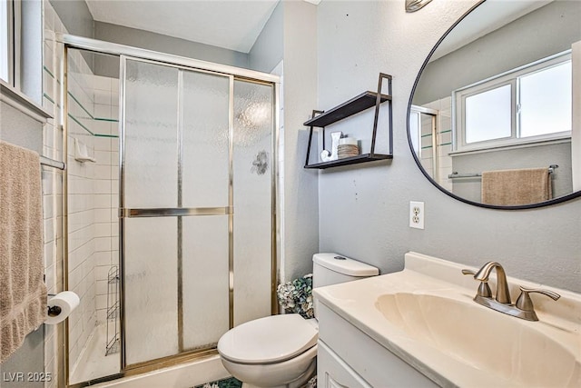 bathroom featuring vanity, a shower with door, and toilet