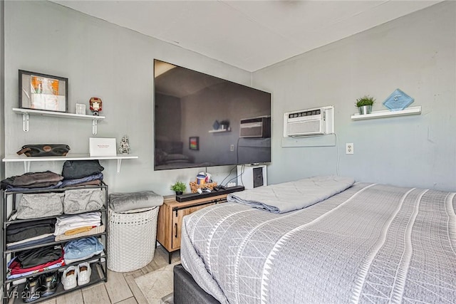 bedroom with a wall unit AC and light hardwood / wood-style floors