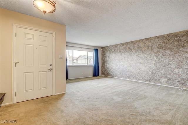 foyer entrance featuring light carpet and a textured ceiling