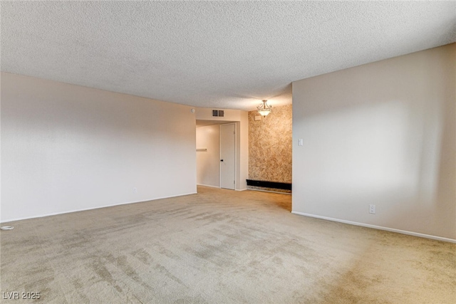 unfurnished room featuring light colored carpet and a textured ceiling