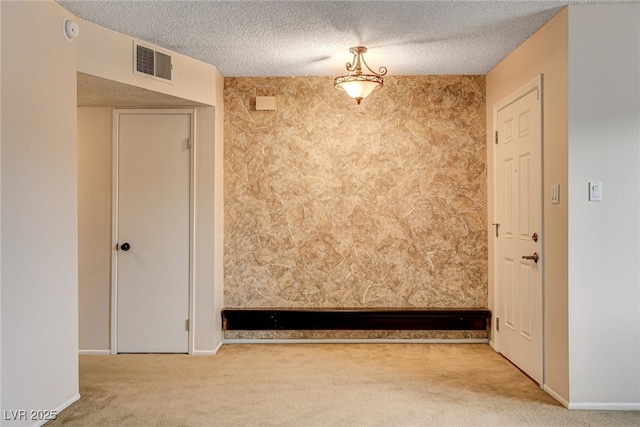 unfurnished room with light colored carpet and a textured ceiling