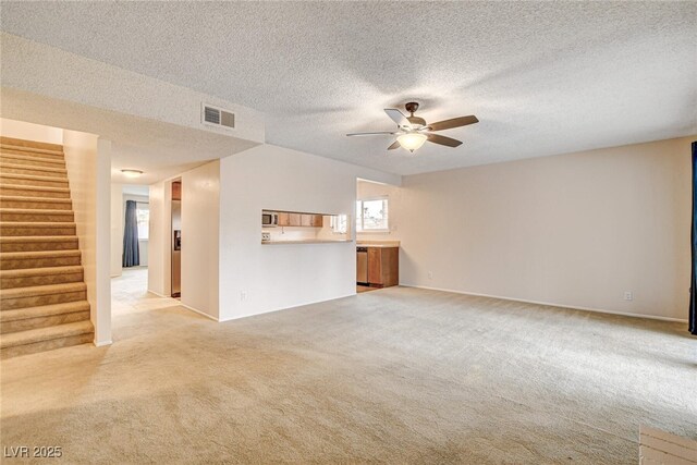 unfurnished living room featuring light carpet, a textured ceiling, and ceiling fan