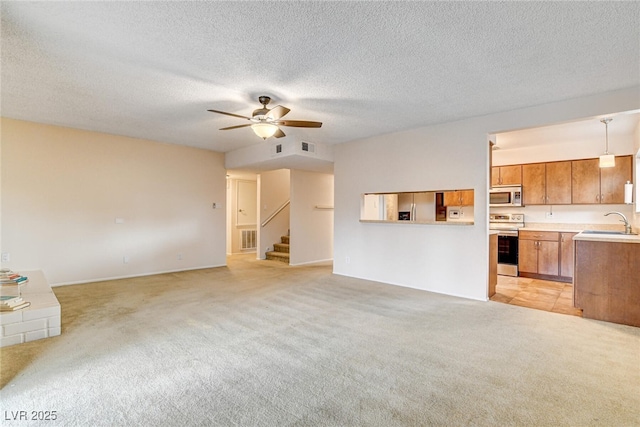 unfurnished living room with sink, light carpet, a textured ceiling, and ceiling fan