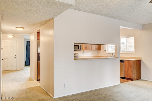 interior space featuring sink, light carpet, a textured ceiling, and kitchen peninsula