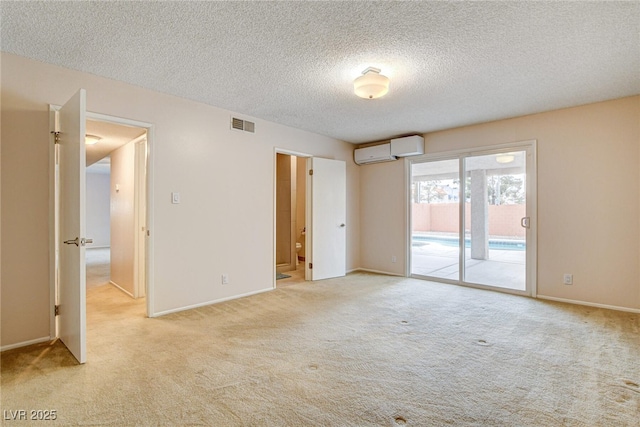 carpeted spare room featuring a textured ceiling and a wall mounted AC