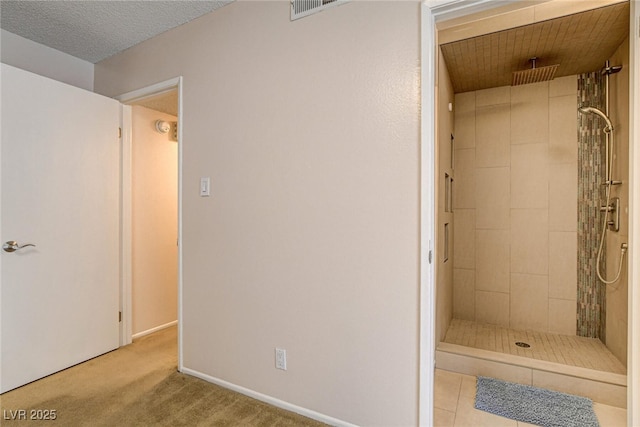 bathroom with tiled shower and a textured ceiling