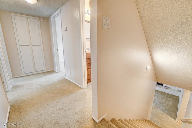 hallway featuring light carpet and a textured ceiling