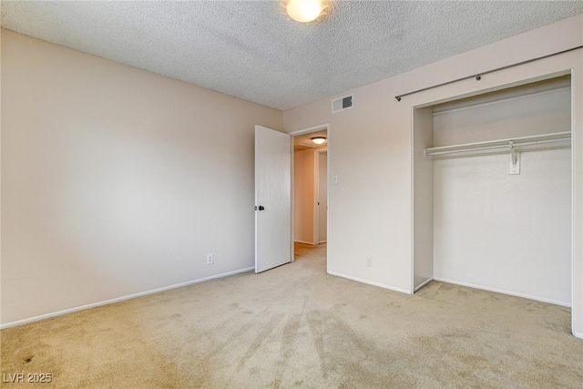 unfurnished bedroom with light colored carpet, a closet, and a textured ceiling