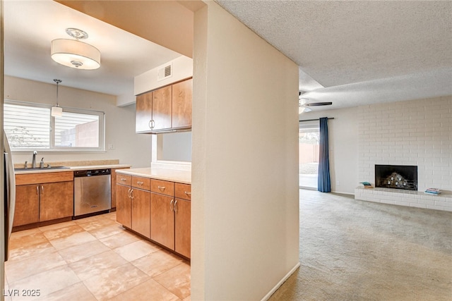 kitchen with decorative light fixtures, sink, stainless steel dishwasher, ceiling fan, and a brick fireplace