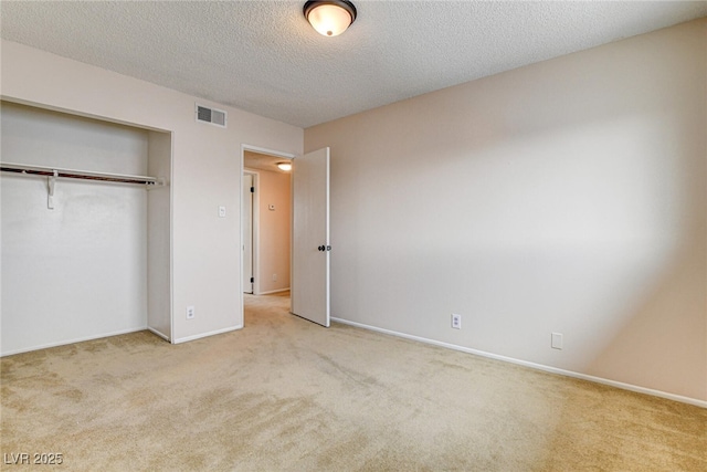 unfurnished bedroom with light colored carpet, a closet, and a textured ceiling