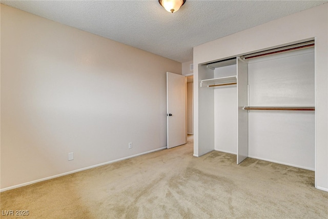 unfurnished bedroom featuring light colored carpet, a textured ceiling, and a closet