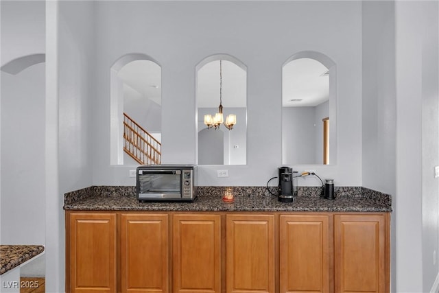 kitchen with hanging light fixtures, dark stone countertops, and a chandelier