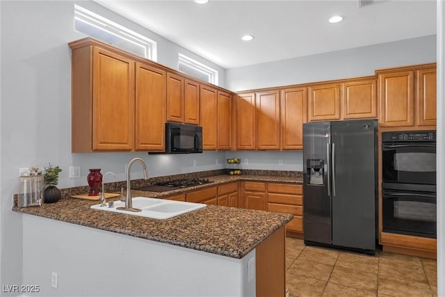 kitchen featuring dark stone countertops, kitchen peninsula, sink, and black appliances