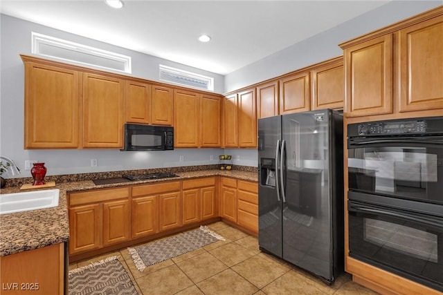 kitchen featuring light tile patterned flooring, dark stone counters, sink, and black appliances