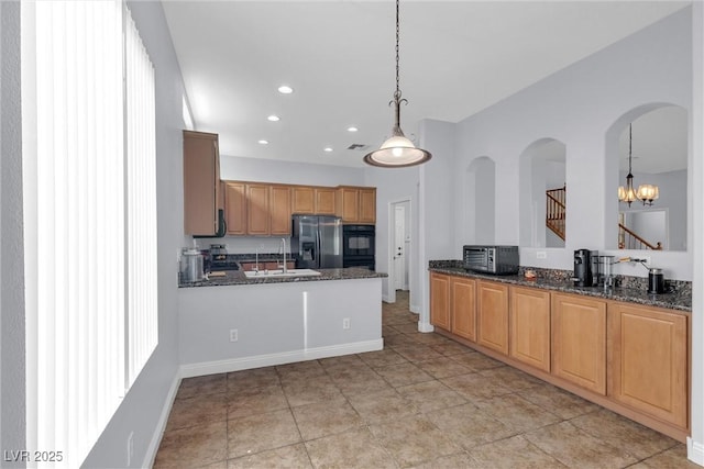 kitchen with stainless steel fridge with ice dispenser, kitchen peninsula, black oven, pendant lighting, and dark stone counters