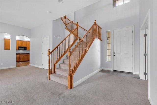 entrance foyer featuring carpet flooring, a wealth of natural light, and a towering ceiling