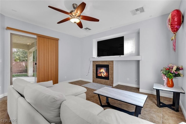 tiled living room with ceiling fan and a fireplace