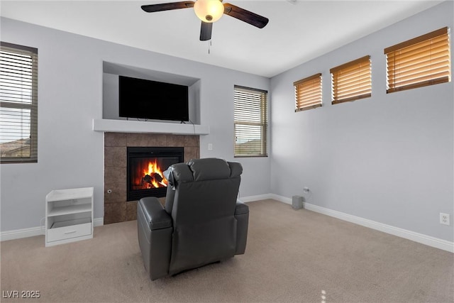 living area featuring a tiled fireplace, light colored carpet, and ceiling fan