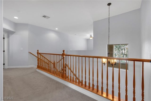 hall with a notable chandelier and light colored carpet