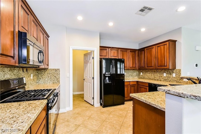 kitchen with sink, backsplash, light tile patterned floors, light stone counters, and black appliances