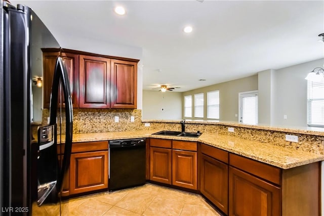 kitchen with sink, light stone counters, black appliances, decorative backsplash, and kitchen peninsula