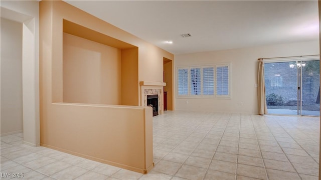 unfurnished living room featuring an inviting chandelier, light tile patterned flooring, and a tile fireplace