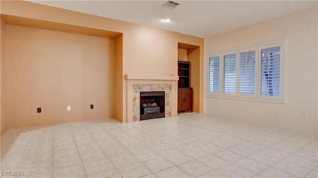 unfurnished living room featuring a premium fireplace and light tile patterned floors