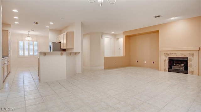 unfurnished living room featuring a tile fireplace and an inviting chandelier