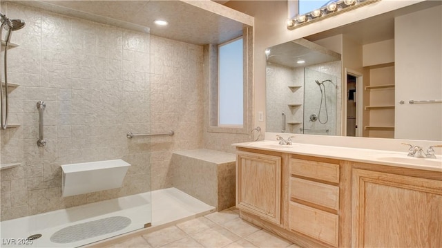 bathroom featuring tile patterned flooring, vanity, and a tile shower