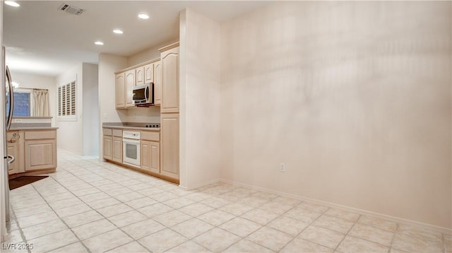 kitchen featuring light brown cabinetry, oven, and black electric cooktop