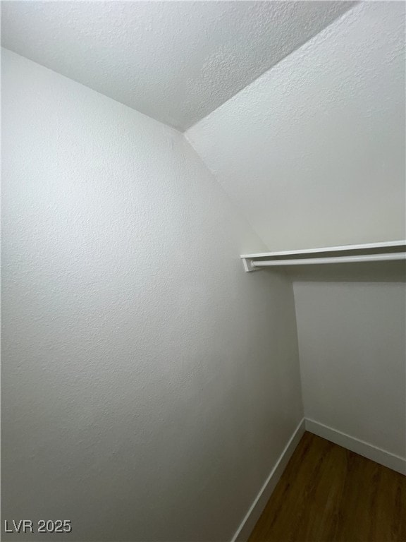 walk in closet with dark wood-type flooring and lofted ceiling