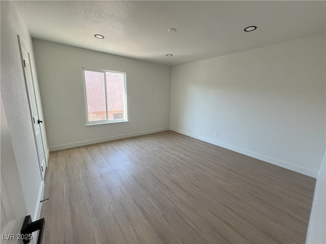 unfurnished room with a textured ceiling and light hardwood / wood-style floors