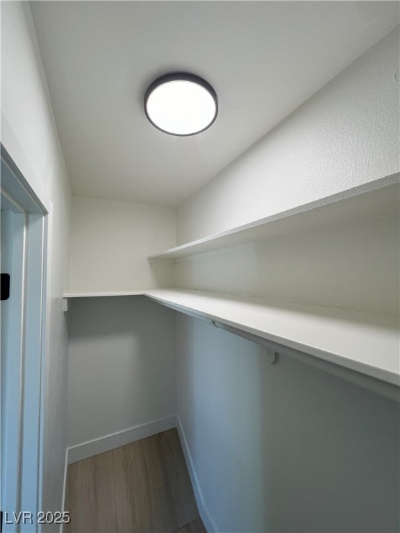 walk in closet with dark hardwood / wood-style flooring and built in desk